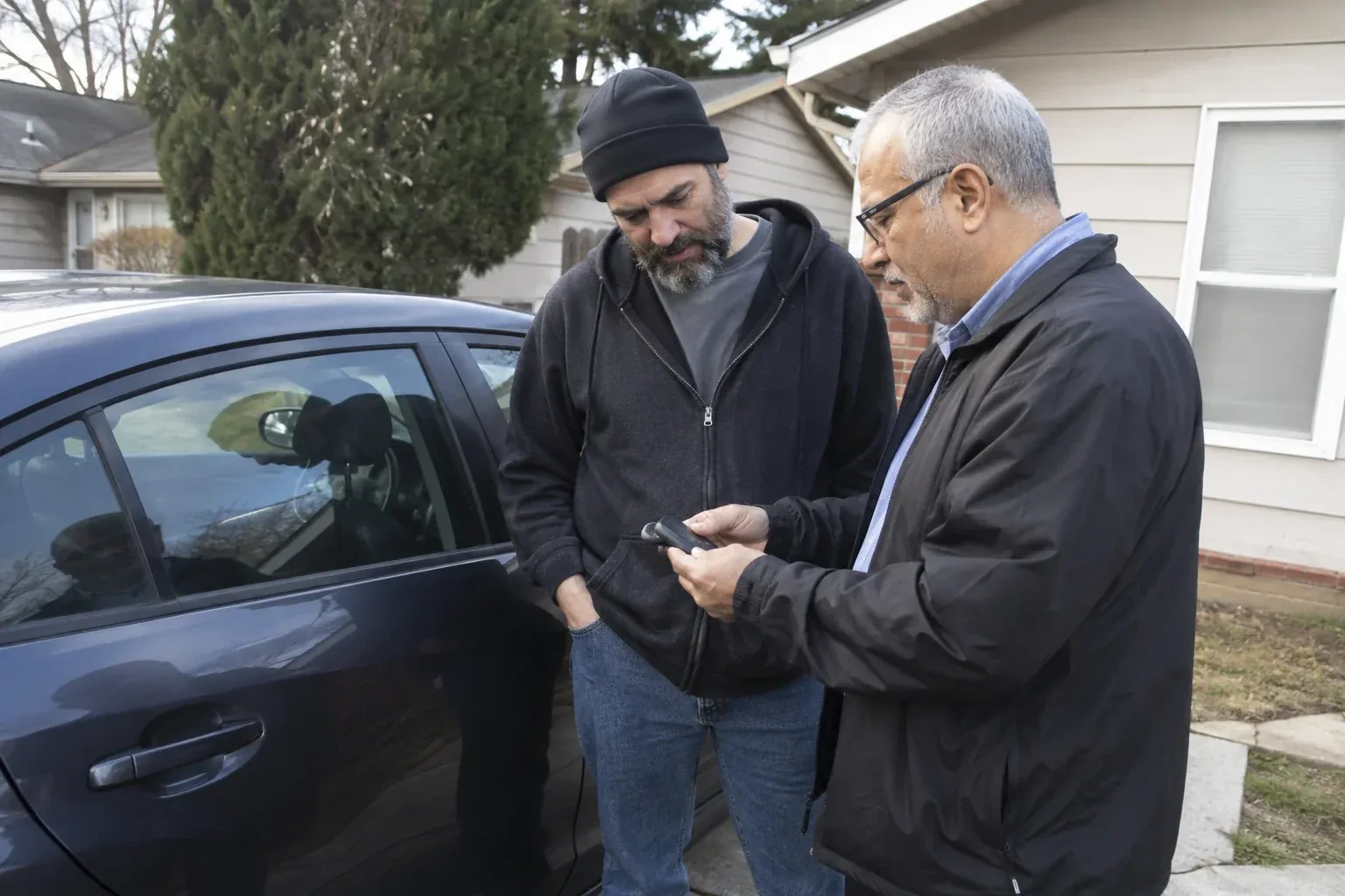 Two adults discussing a key fob beside a parked car. — Car Lockout Service, Springwater